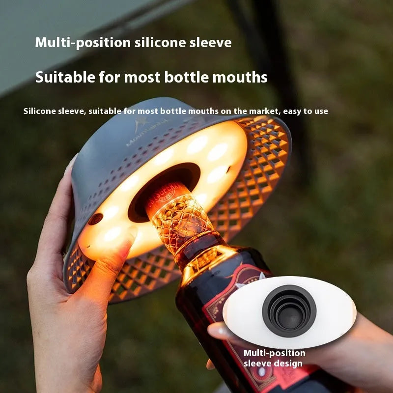 Beige rechargeable wine bottle shaped camping lantern with USB-C port and switch, shown illuminated.