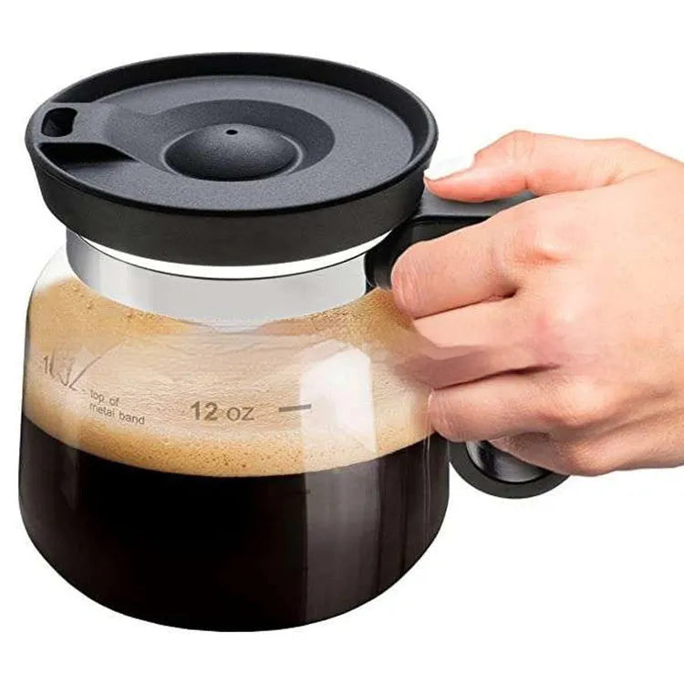 Transparent borosilicate glass coffee maker with black silicone lid on a stovetop