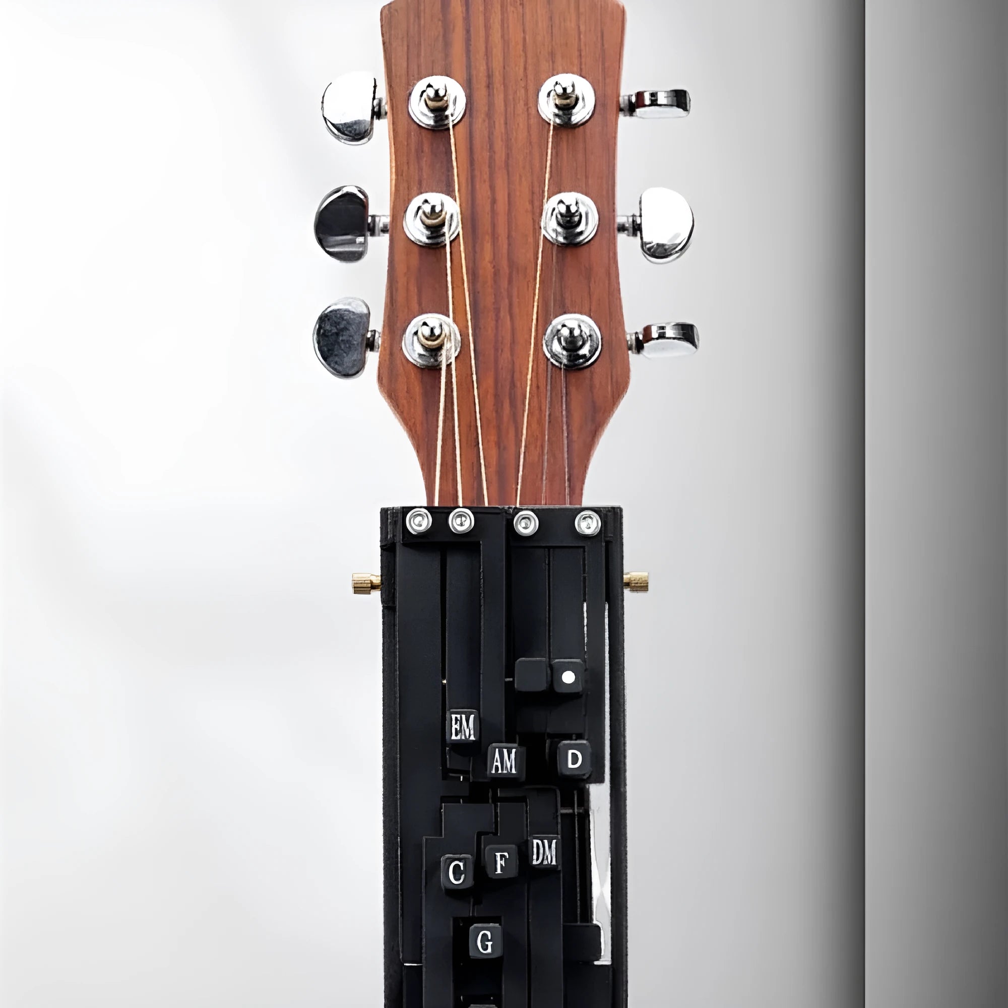 Black automatic chord device for folk guitar, showing the auxiliary gear mechanism for novice practice.