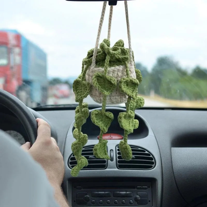 Green and white crocheted wool car plant decoration with a white hanging rope.