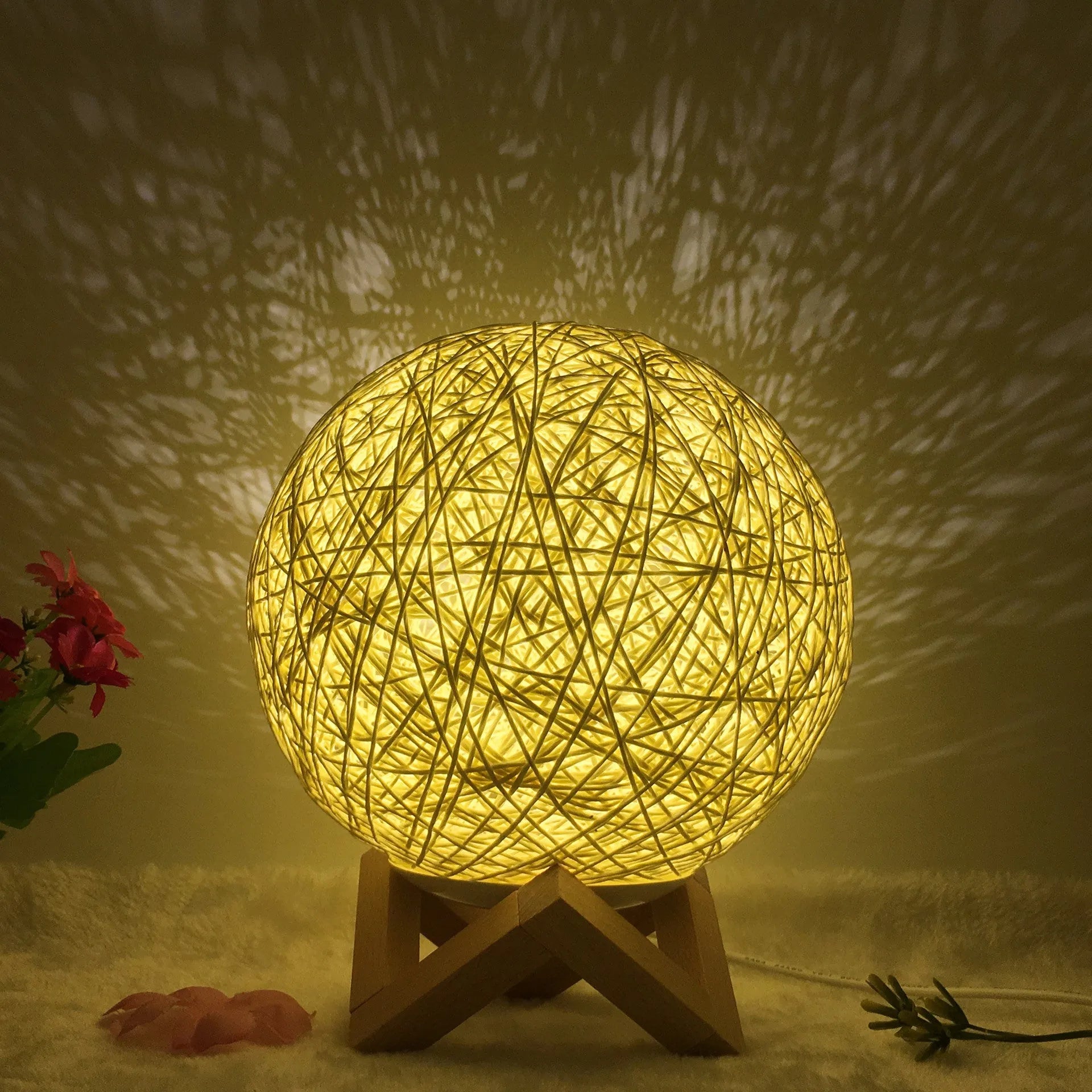 White hand-knit rattan ball lamp with USB cable and remote control on a wooden table.