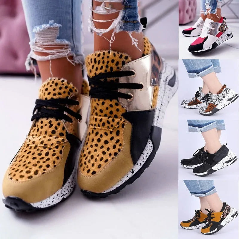 Women's black suede wedge sneakers with a low-cut ankle and round toe on a wooden floor.