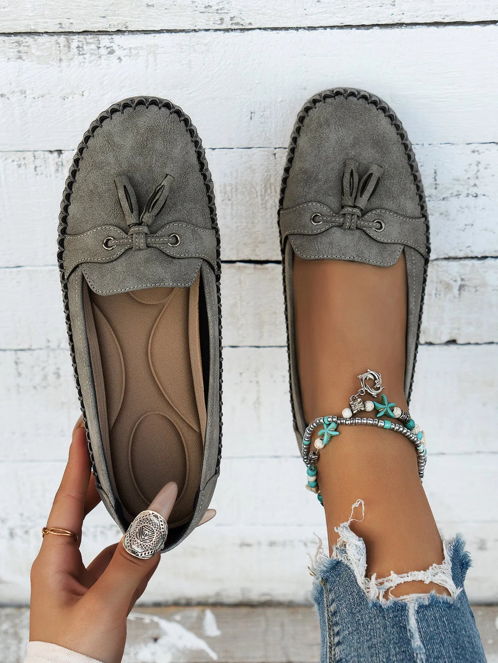 Women's suede flat shoes with a bow detail in pink, shown from the side on a plain background.