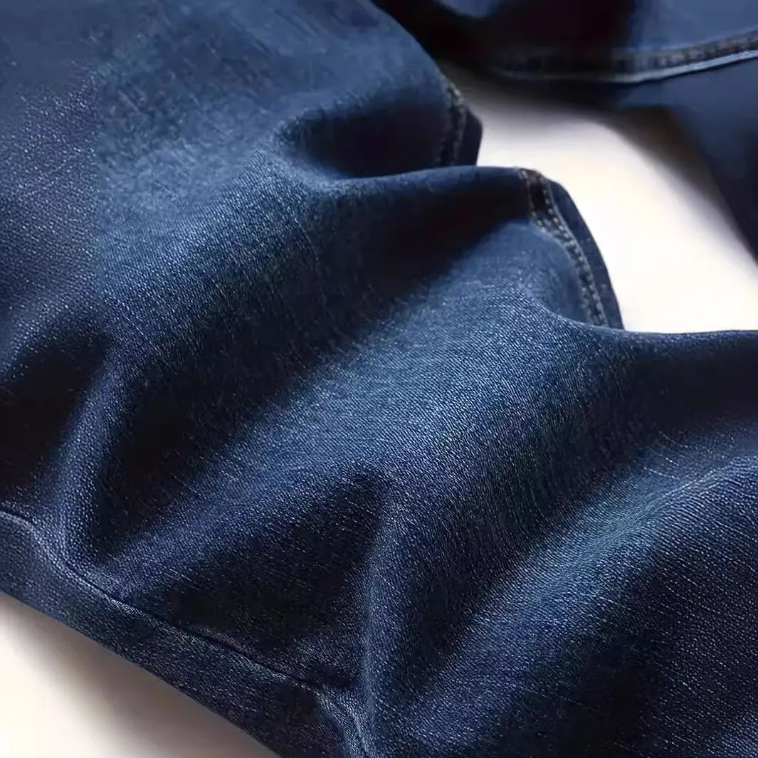 Men's dark blue slim-fit skinny jeans with a zip fly and mid-rise waist on a plain background.