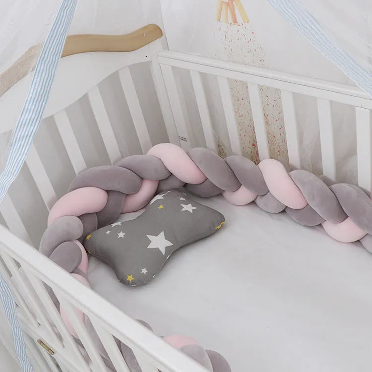 Braided knot style crib bumper in spandex velvet, wrapped around white cot rails in a nursery.