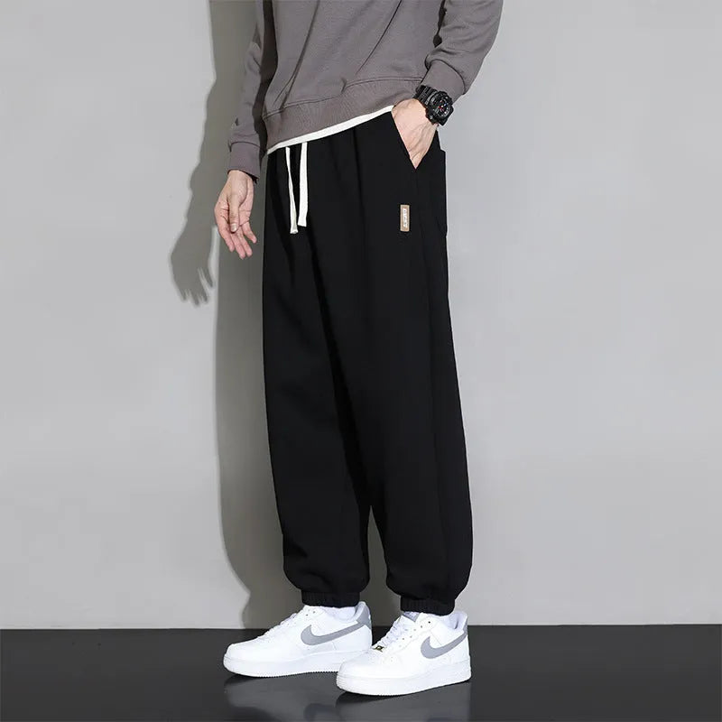 Men's loose grey cotton blend sports trousers with a drawstring waist on a hanger.