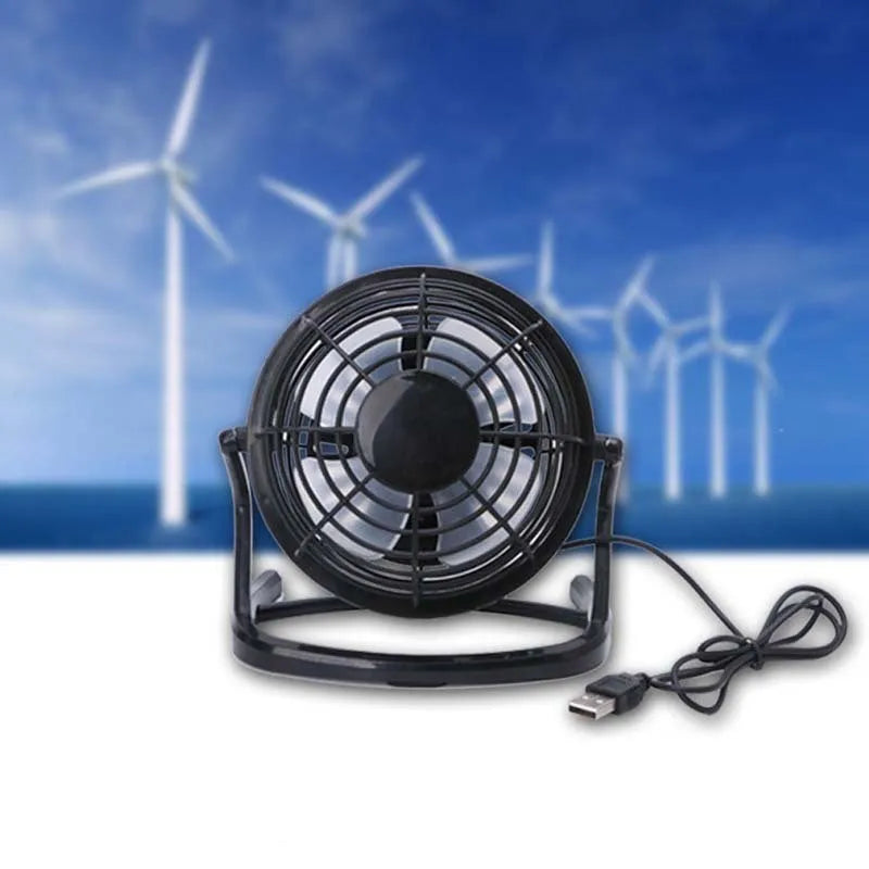 Compact black mini USB desk fan with adjustable tilt on a desk next to a laptop.