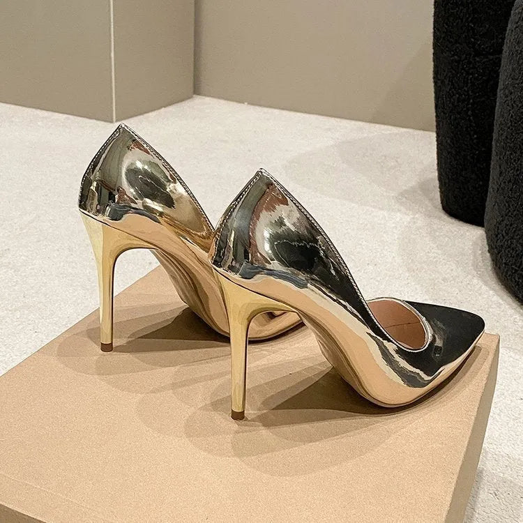 Gold and silver pointed toe stiletto heel slip-on pumps on a plain background