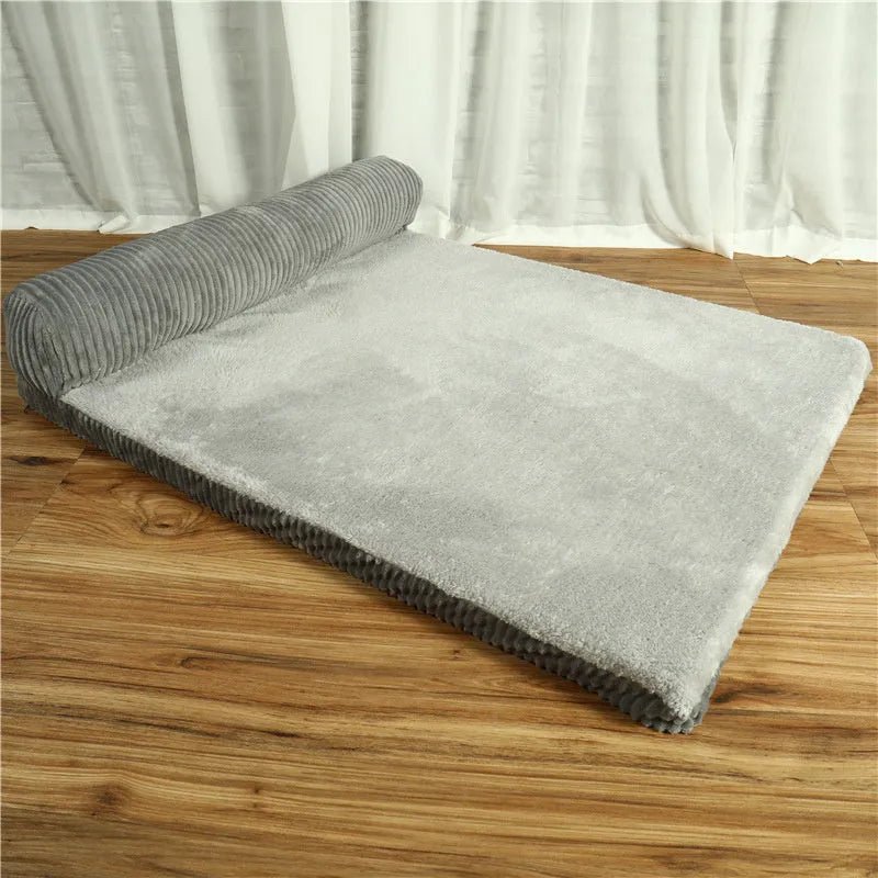 A corduroy dog sofa bed with a raised bolster side, shown in a grey colour on a wooden floor.