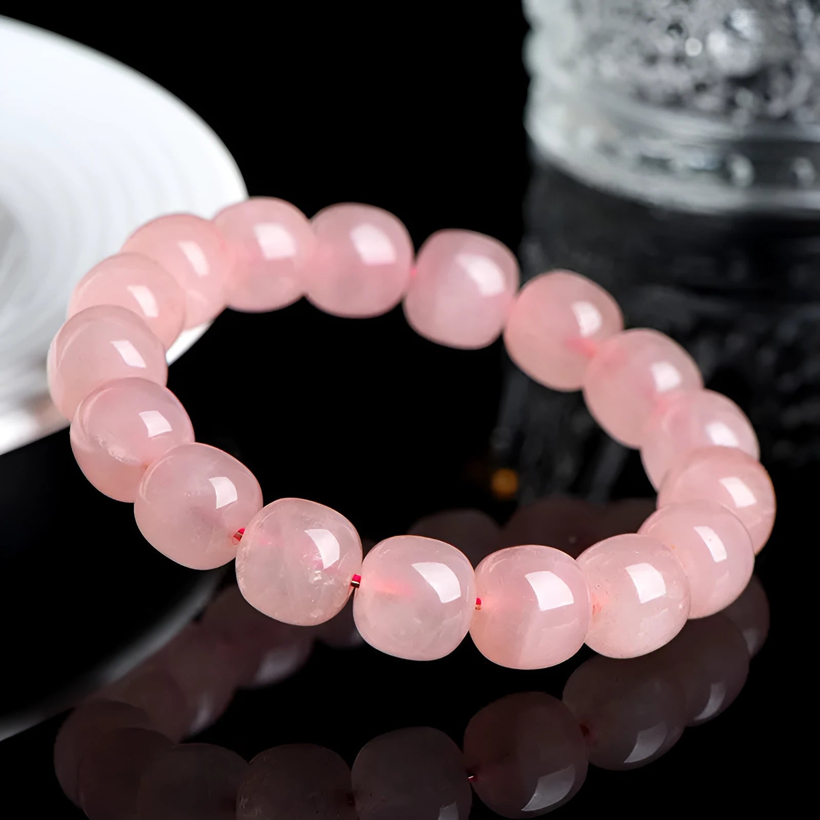 Pink natural crystal bracelet with barrel-shaped beads on a wrist.
