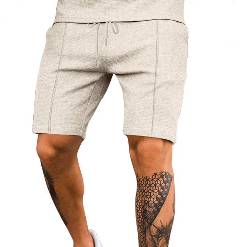 Solid colour five-point polyester sports shorts in khaki with elastic waistband, side view on model