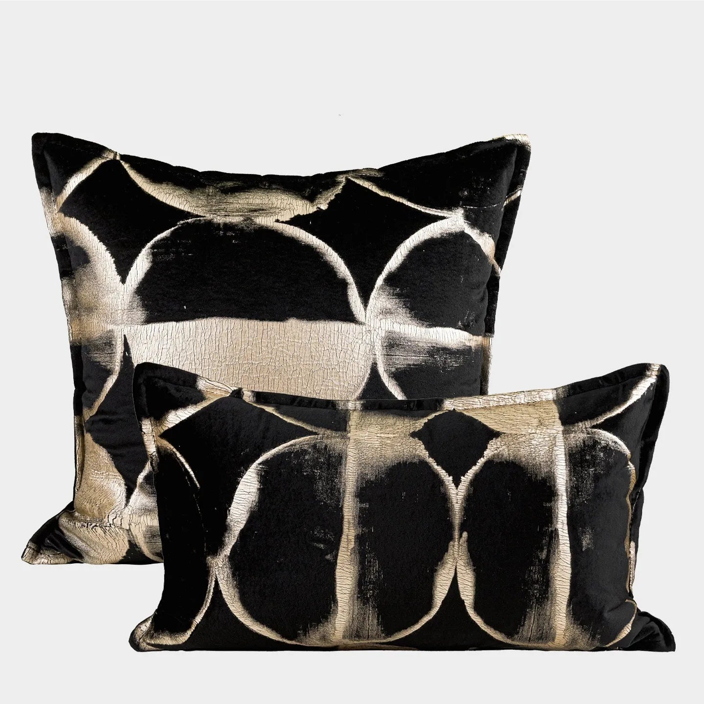 Black and gold abstract pattern decorative square and waist pillow cushions on a grey sofa.