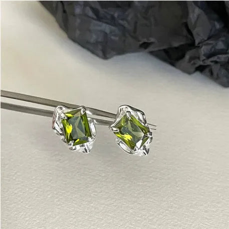 Pair of liquid olive green electroplated alloy stud earrings for women on a neutral background