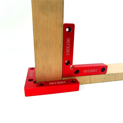Silver aluminium right angle block clamped to a wooden workbench next to a jigsaw, showing scale markings.