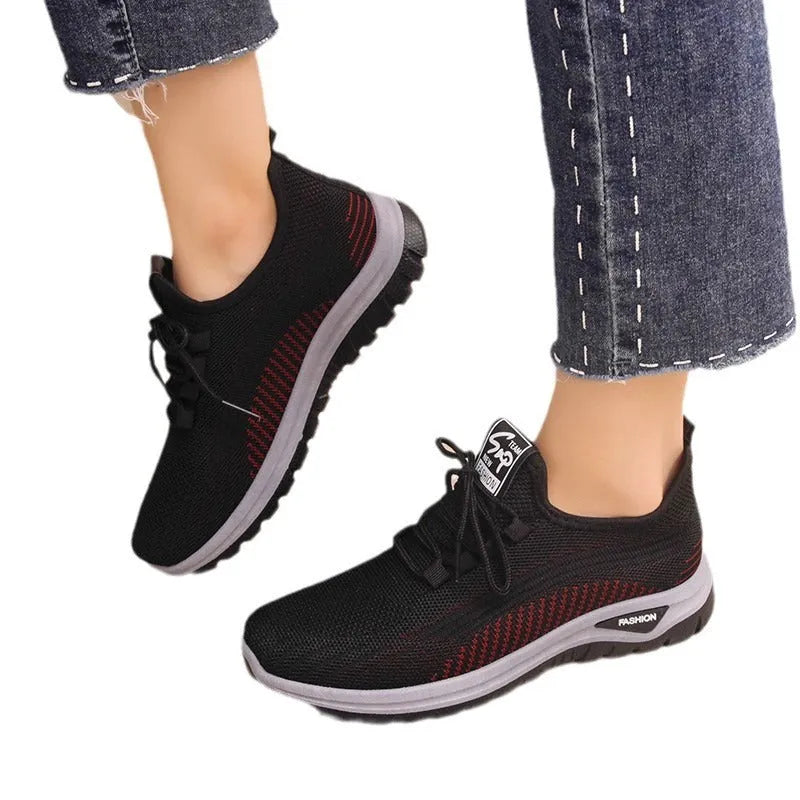 Women's black mesh sneakers with cross strap detail and round toe on a rubber sole.