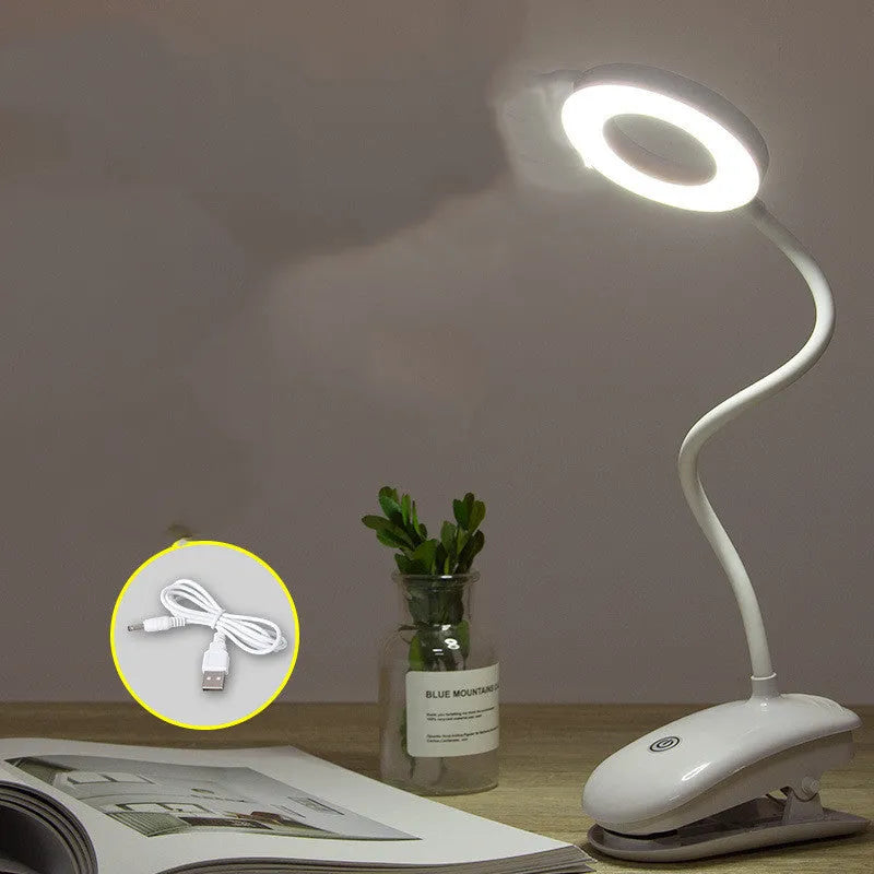Modern clip-on rechargeable LED desk lamp with touch switch and plastic shade in use on a desk.