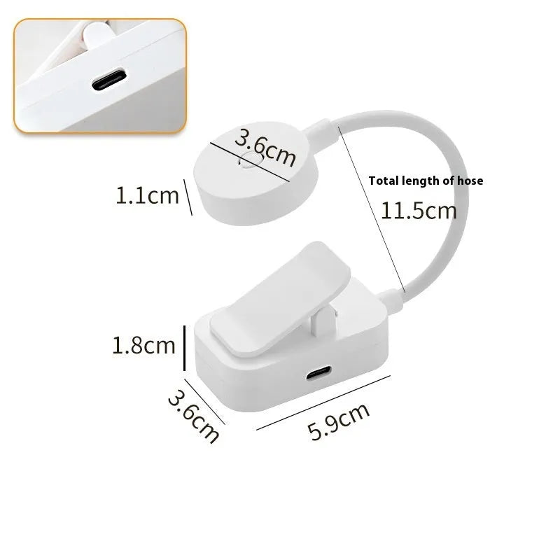 White plastic rechargeable LED book clip light clipped onto a book with USB charging cable