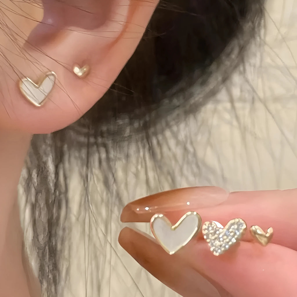 Three pairs of heart-shaped alloy earrings in gold, black, pink, and black-white colours
