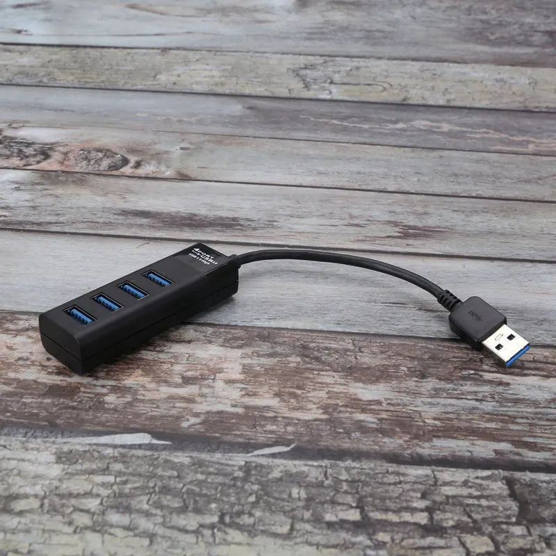 Black USB 3.0 hub with 4 Type-A ports and a 30cm connected cable on a desk.
