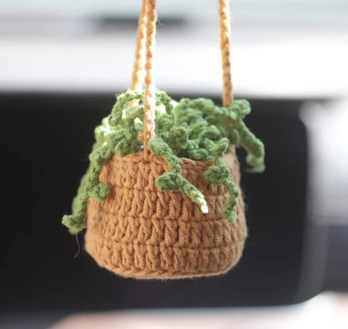 Green and white crocheted wool car plant decoration with a white hanging rope.