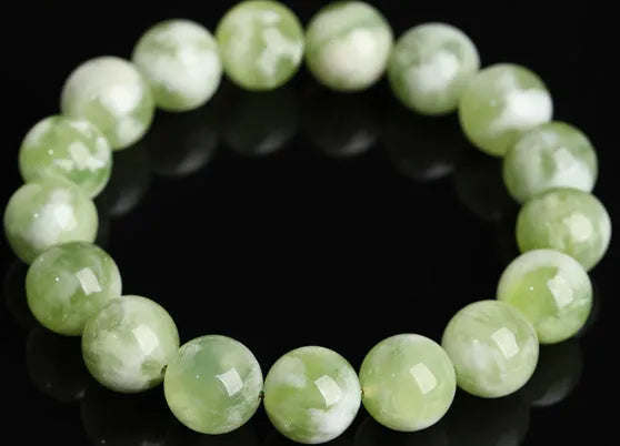 Green milk-in-water Xiuyan jade bracelet with polished geometric beads on a wrist.