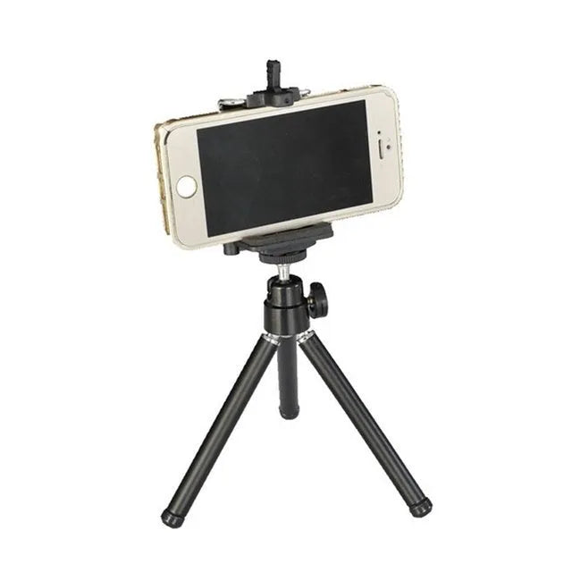 Mini aluminium tripod extended with ball head, shown alongside a U-shaped smartphone clip on a table.