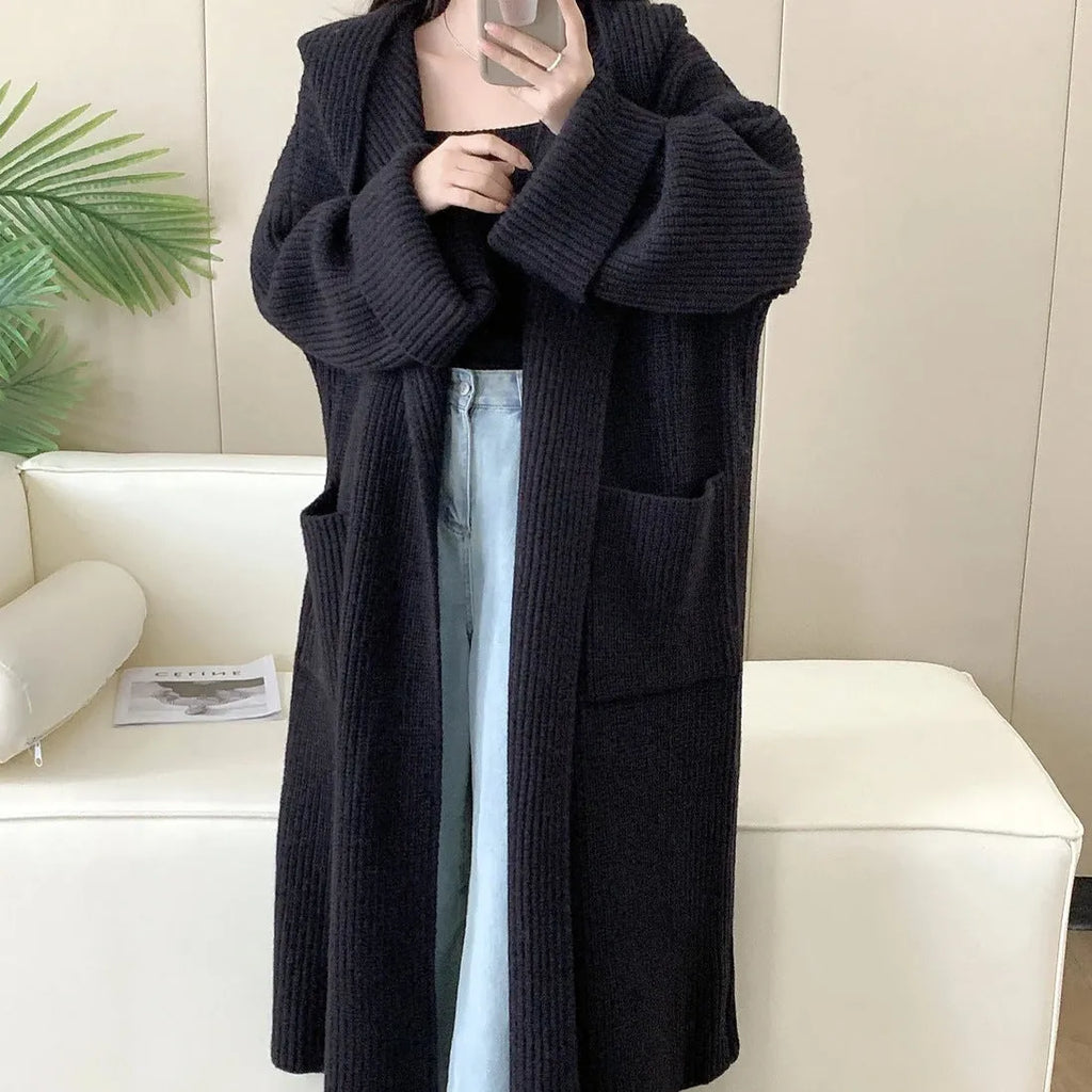 Woman wearing a longline loose grey hooded cardigan coat with raglan sleeves.