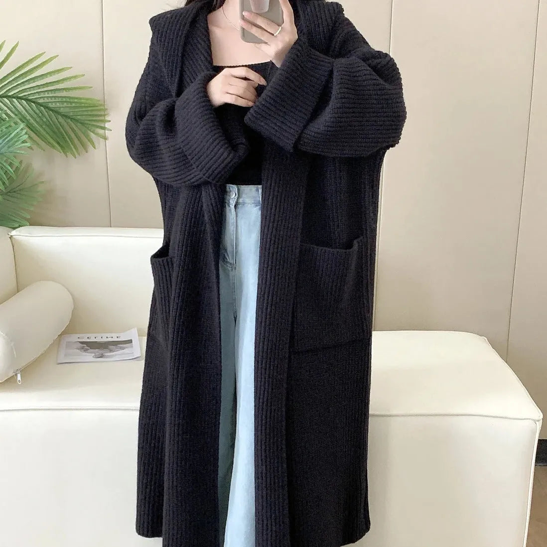 Woman wearing a longline loose grey hooded cardigan coat with raglan sleeves.