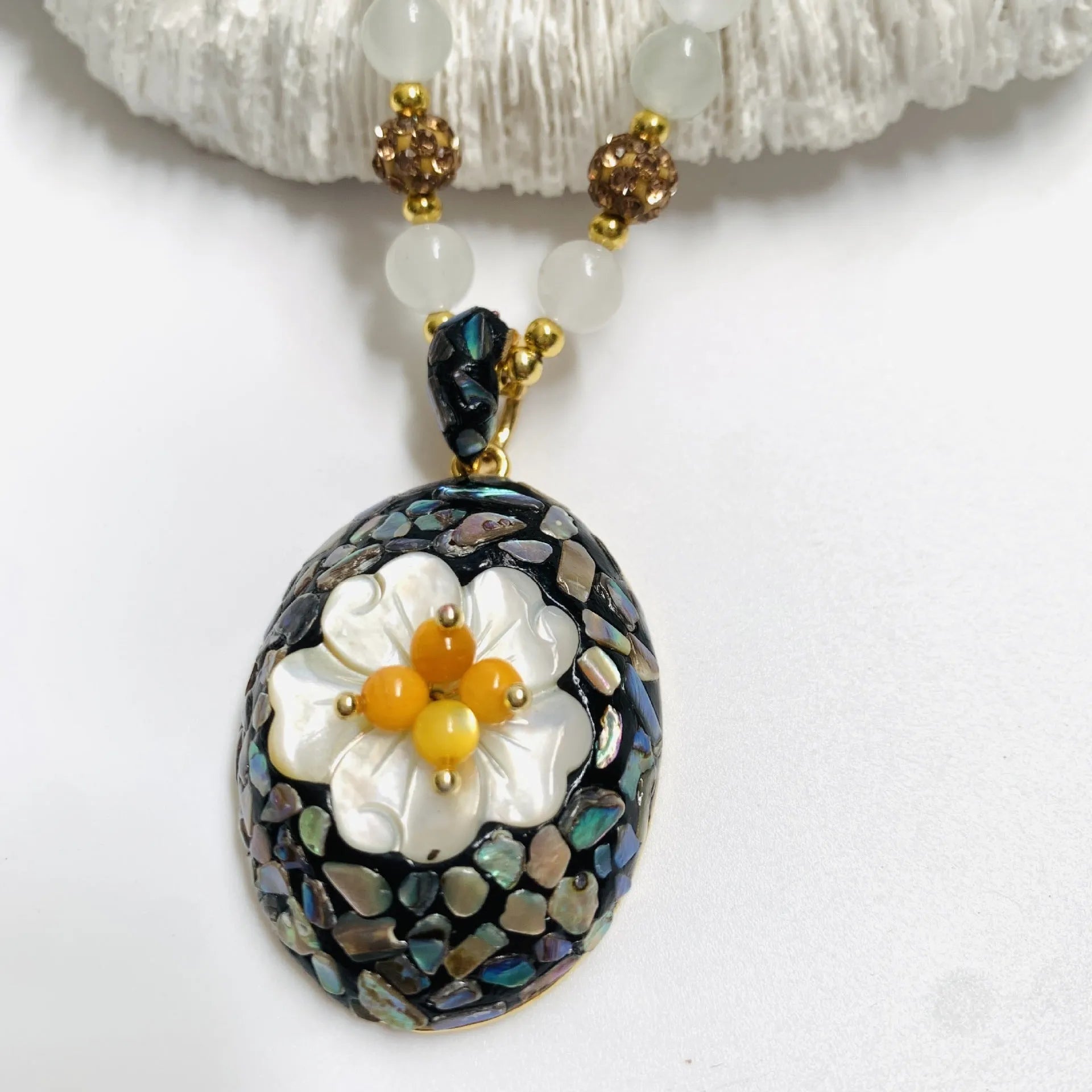 Original design mother-of-pearl lacquer shell necklace with rhinestone twist chain on display