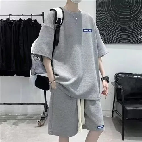 Man wearing a grey waffle-textured short-sleeved top and matching shorts from a casual leisure suit.
