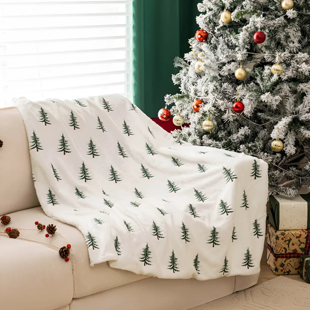 White plush sofa blanket with embroidered Christmas tree design on a sofa