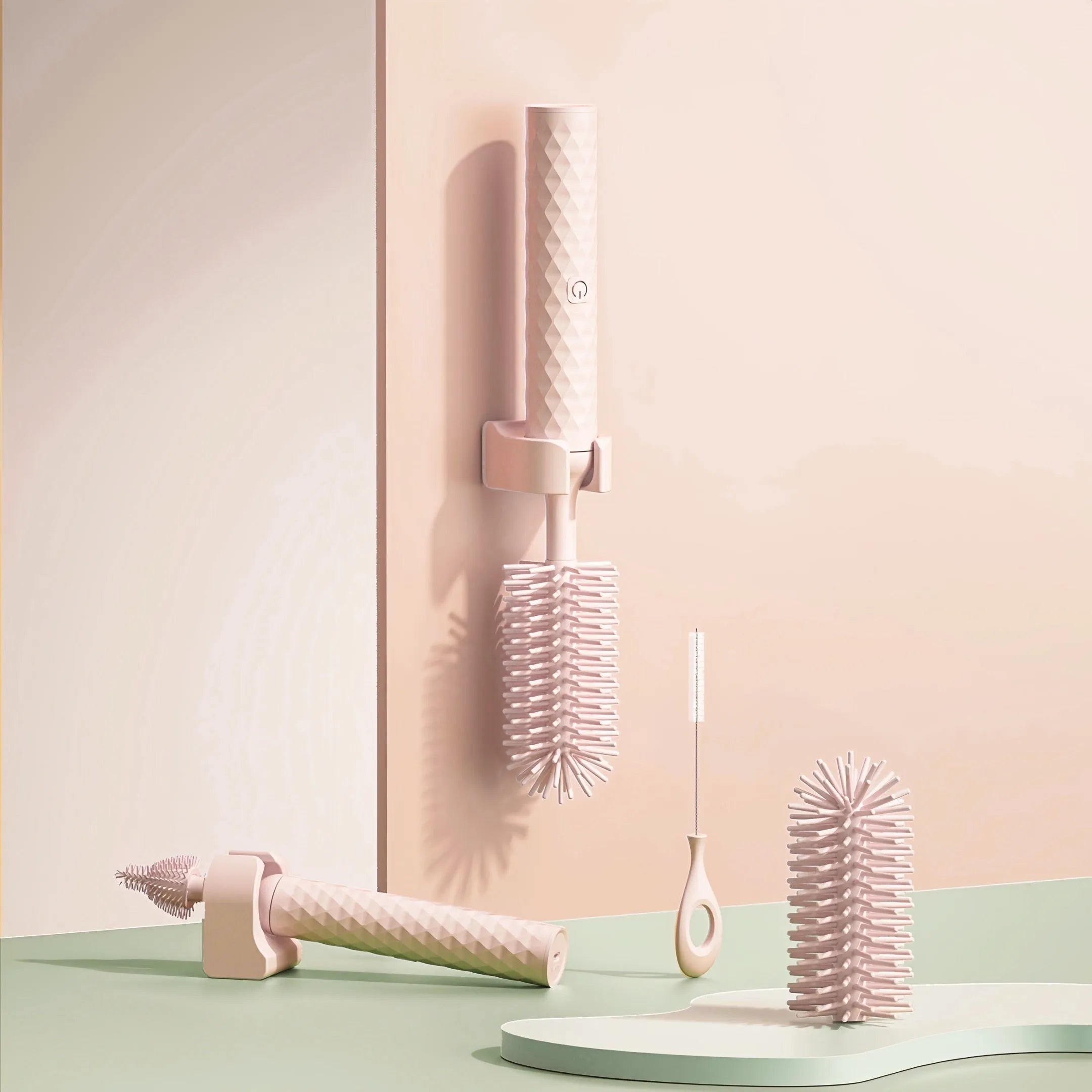 Pink and green electric rotating bottle cleaning brush with silicone bristles on a white background.