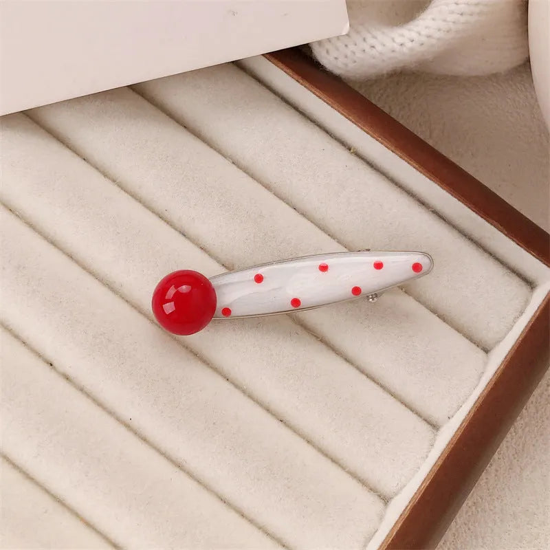 Red handmade hair clip shaped like a 3D love heart with vintage white dots, on a white background.