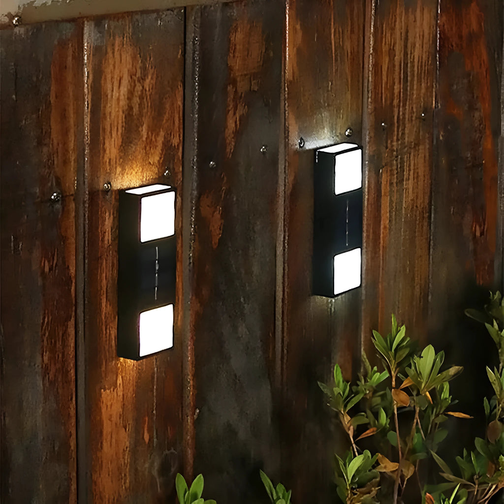 White solar wall lamp with bidirectional sensor mounted on a brick wall, showing warm light illumination