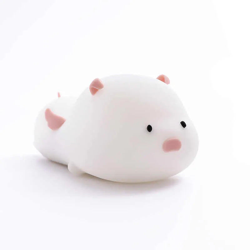 Pink silicone night light in the shape of a sleeping pig on a table.