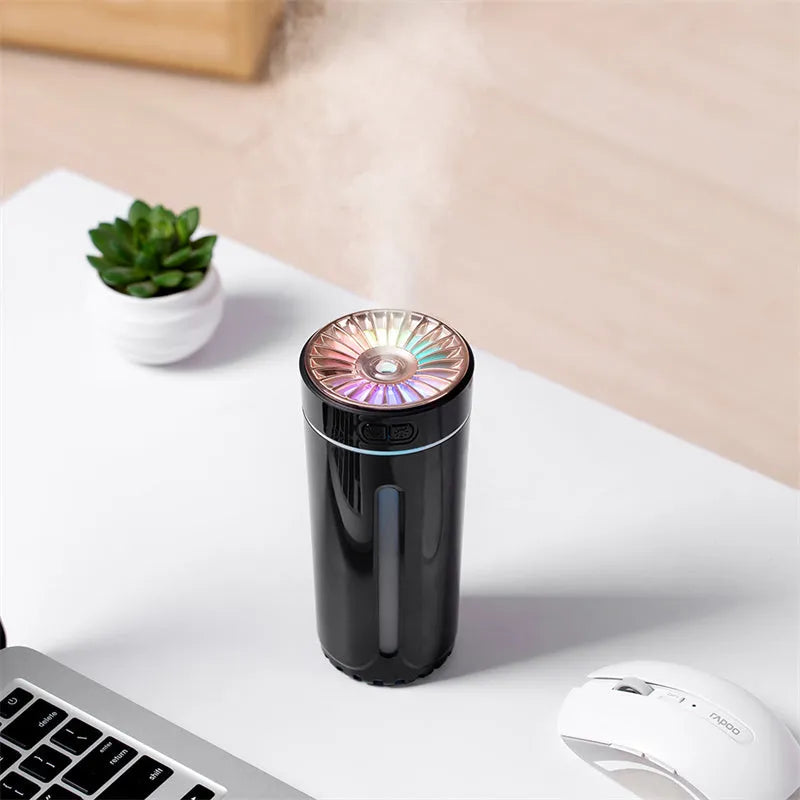 Black wireless USB car humidifier with colourful LED lights on a desktop next to a cup holder.