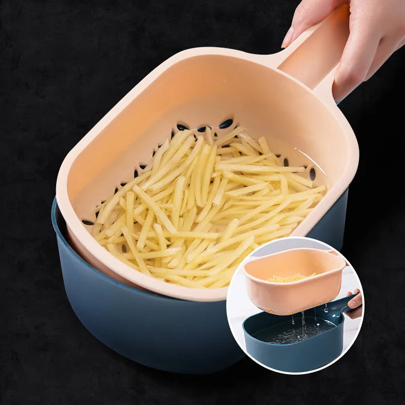 Dark blue manual vegetable cutter with four blades, hand guard, and drain basket on a kitchen counter