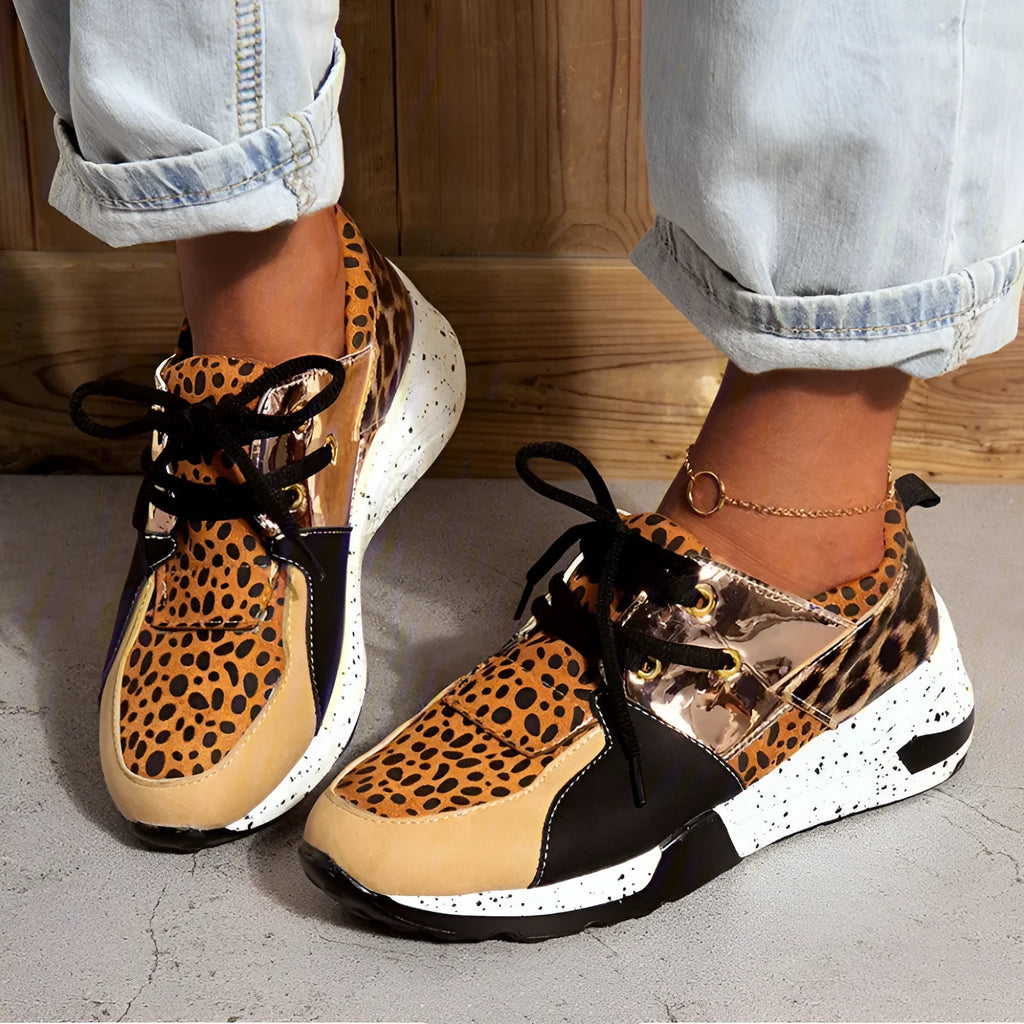 Women's black suede wedge sneakers with a low-cut ankle and round toe on a wooden floor.