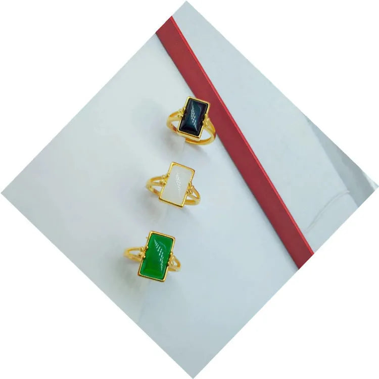 Close-up of an adjustable brass gold-plated ring with an electroplated finish and a green artificial gemstone inlay.