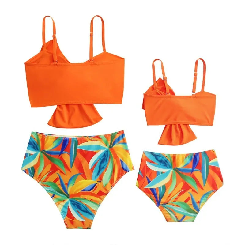 Women's big bow bikini and swim trunks set in a colourful print, shown in orange colour.