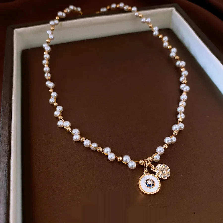 Gold electroplated necklace with round zircon and imitation pearl geometric pendant on an adjustable chain.