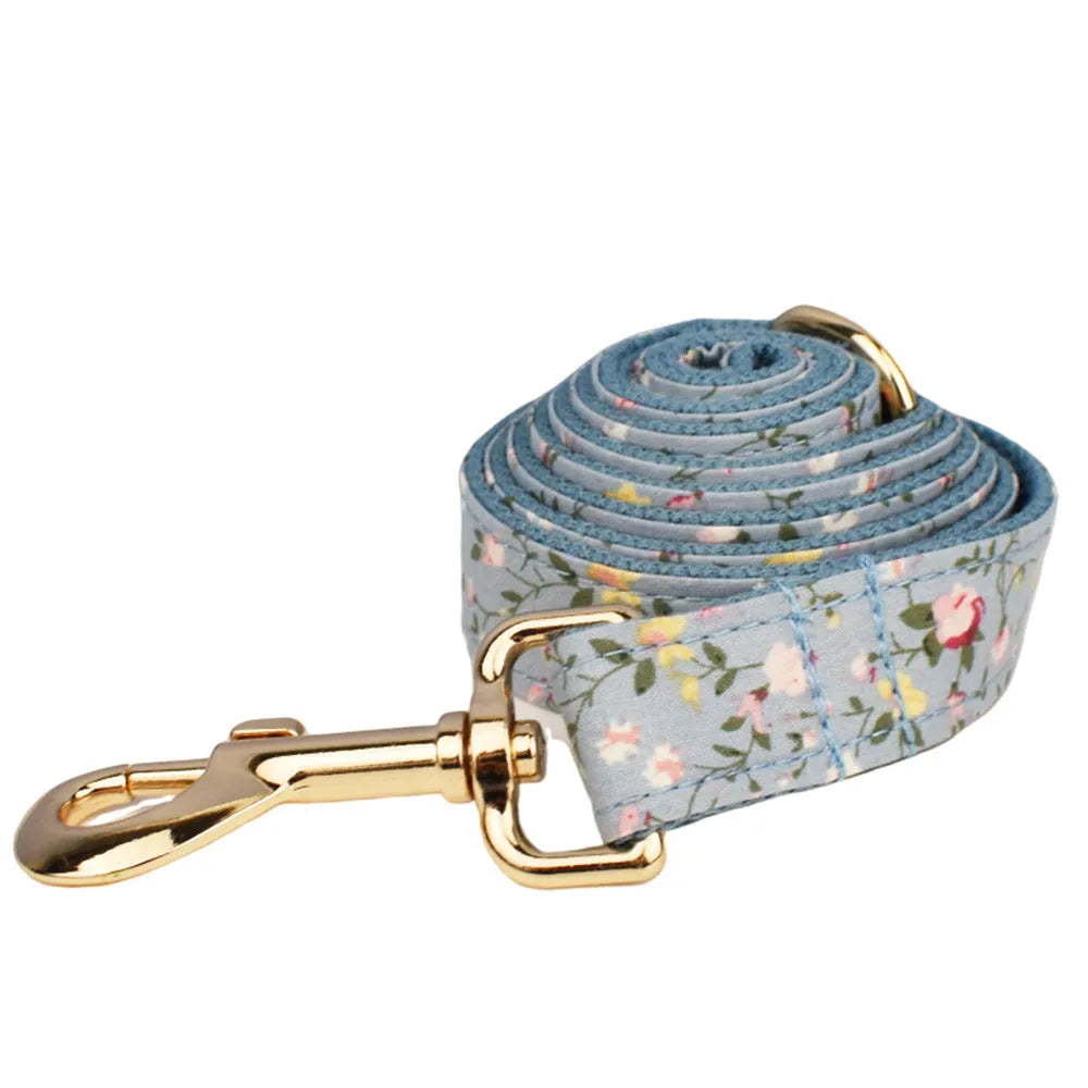 Floral print dog collar and leash set with matching bow, vest, and poop bag holder.