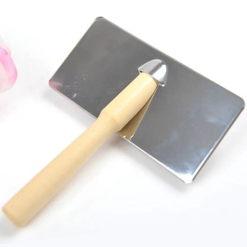 Red pet needle comb with wooden handle and stainless steel pins on a grooming surface