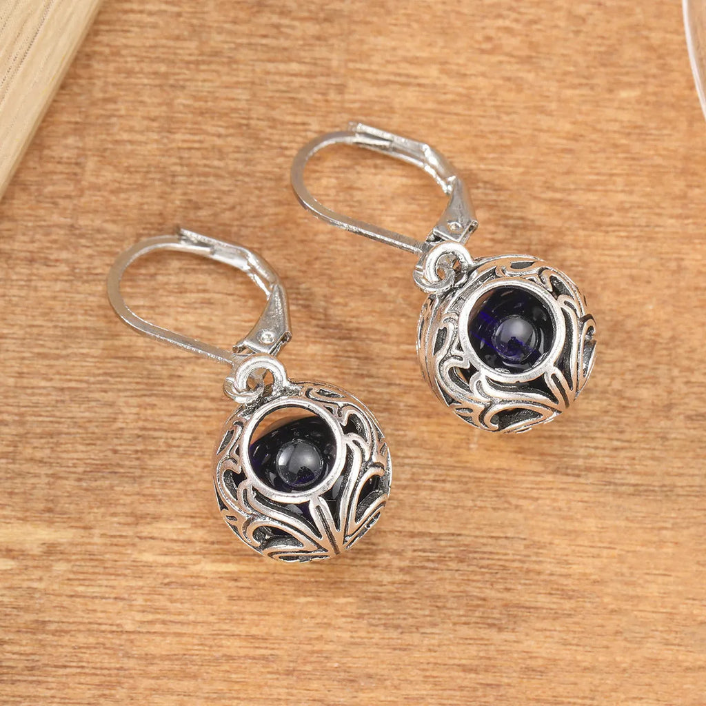Silver tone geometric earrings with hollow pendant designs and blue gemstone accents