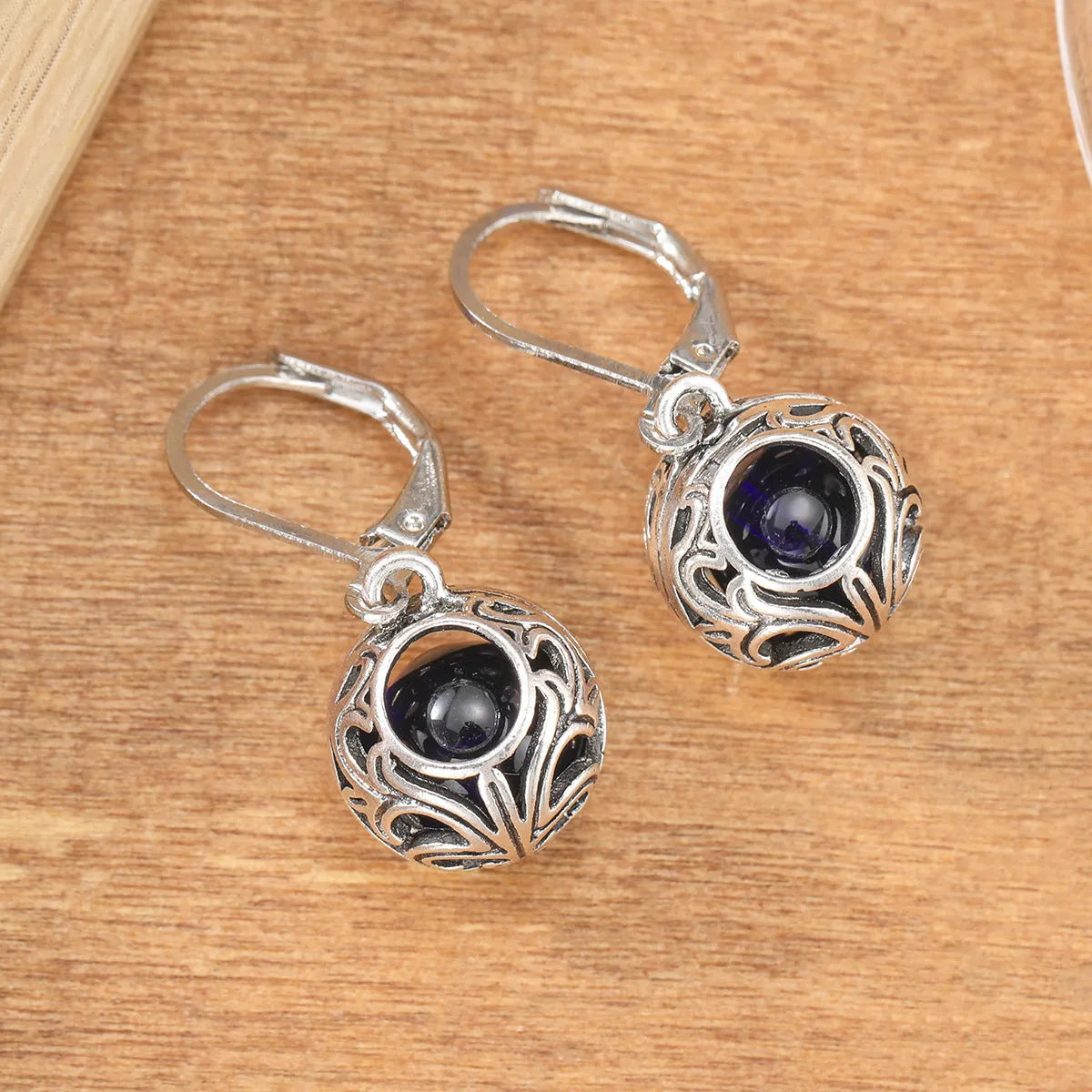 Silver tone geometric earrings with hollow pendant designs and blue gemstone accents