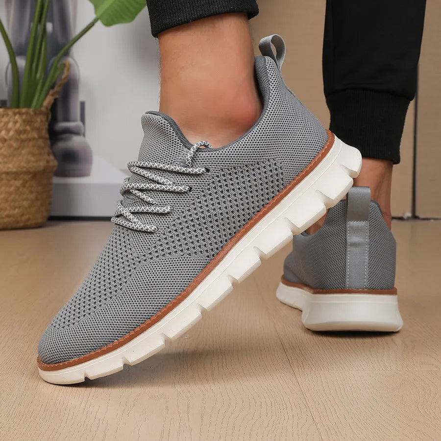 Men's grey and black mesh fabric casual sneakers with a round toe and low heel on a plain background.