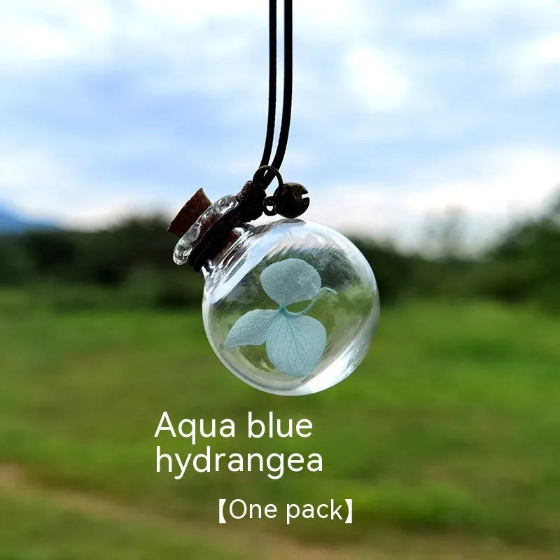 Glass car perfume pendant with preserved flowers inside, shown in a selection of different floral colours.