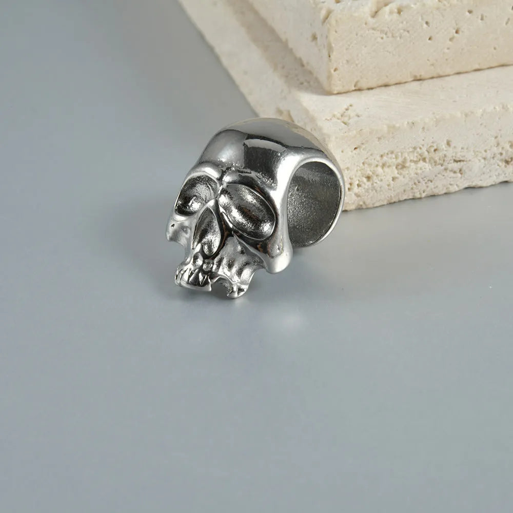 Close-up of a stainless steel hollow skull earring with an electroplated finish, shown alongside a Buddha head design option.