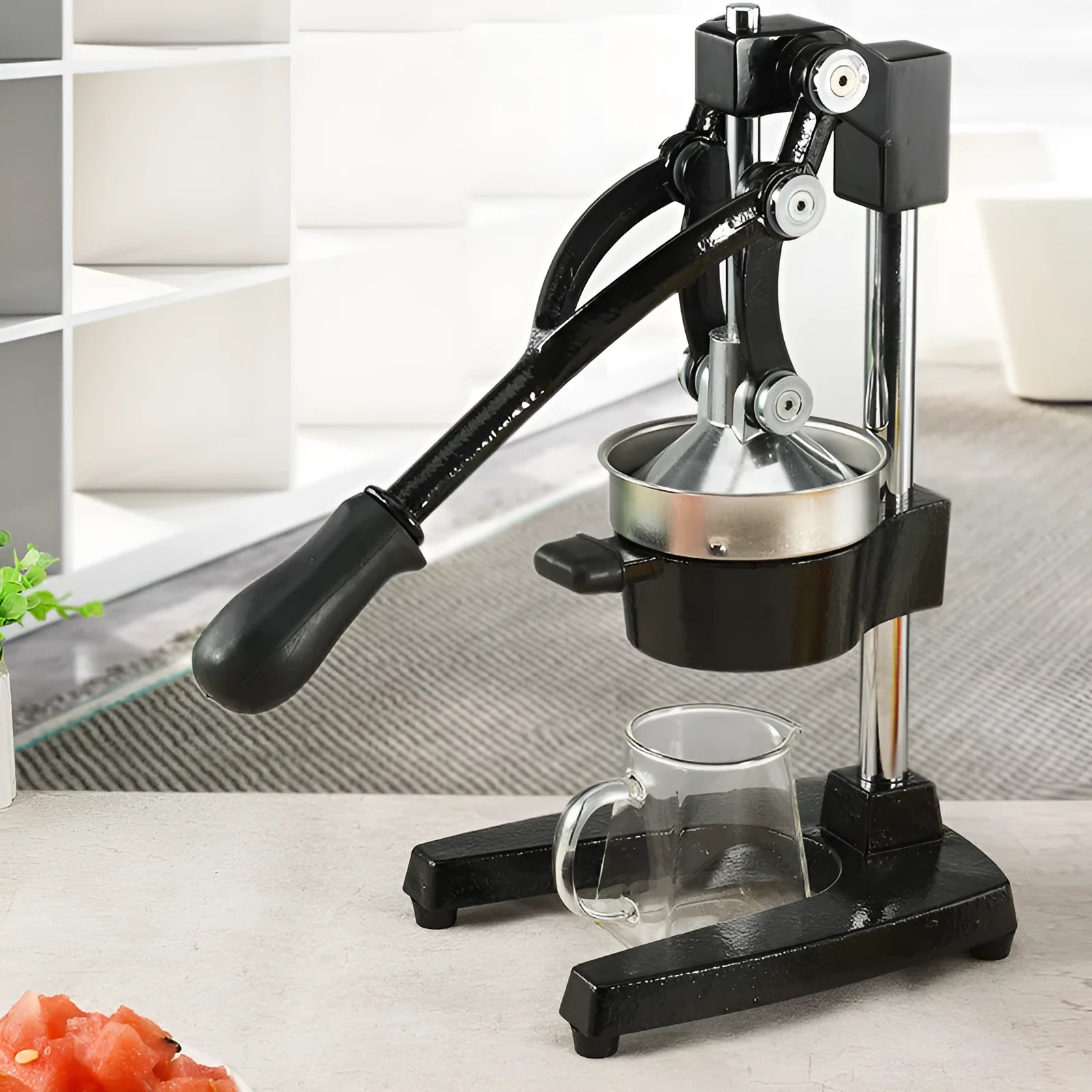 A tall black cast iron manual citrus juicer with a stainless steel strainer on a kitchen counter.