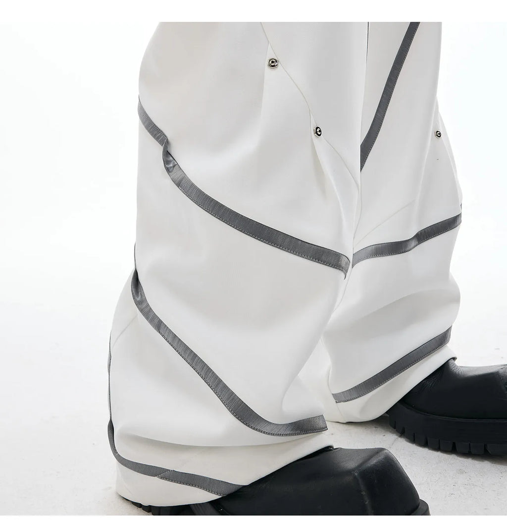 Men's black polyester trousers with three-dimensional cut and metal striped rivets on the pleats.